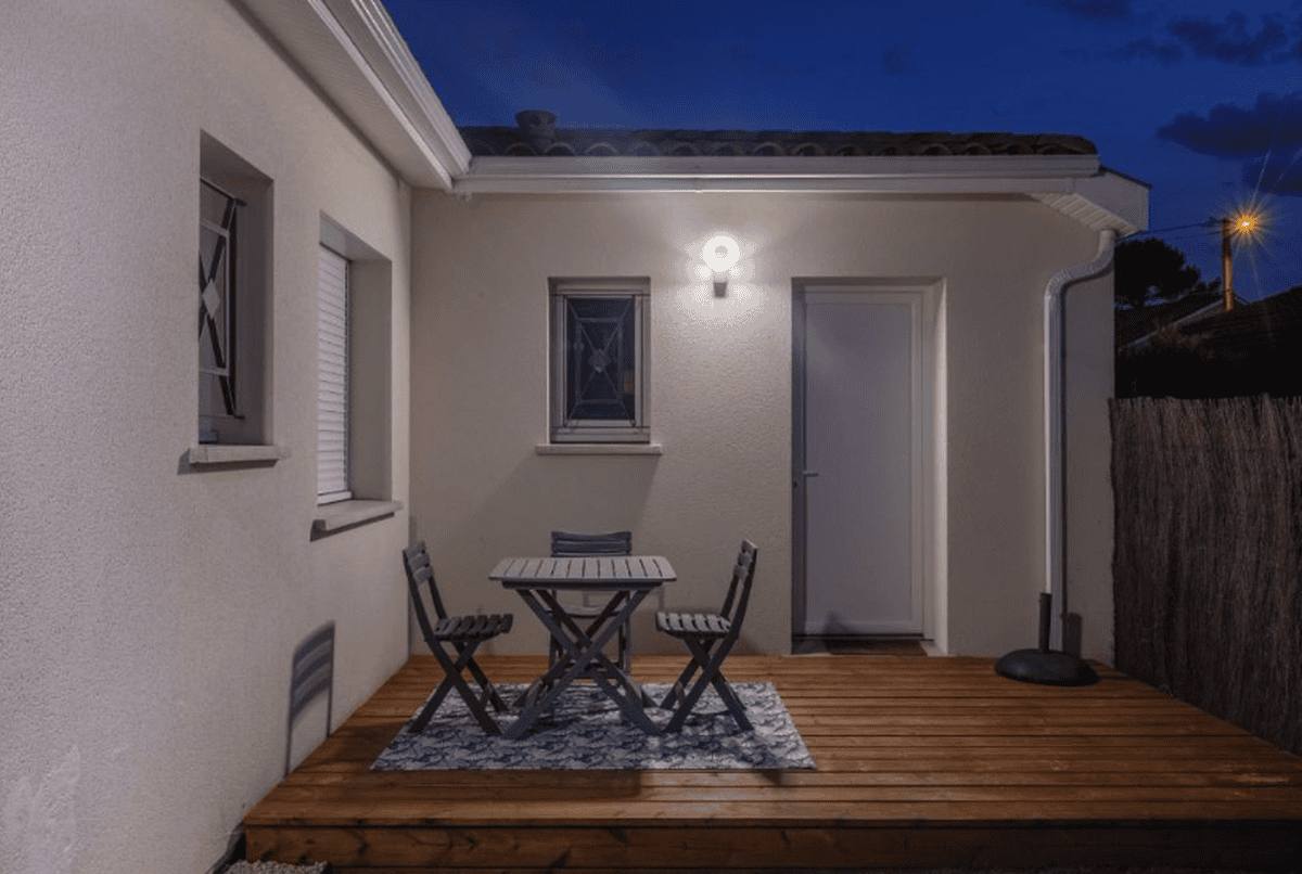 La terrasse du studio le soir, éclairée par l'applique au-dessus de la porte